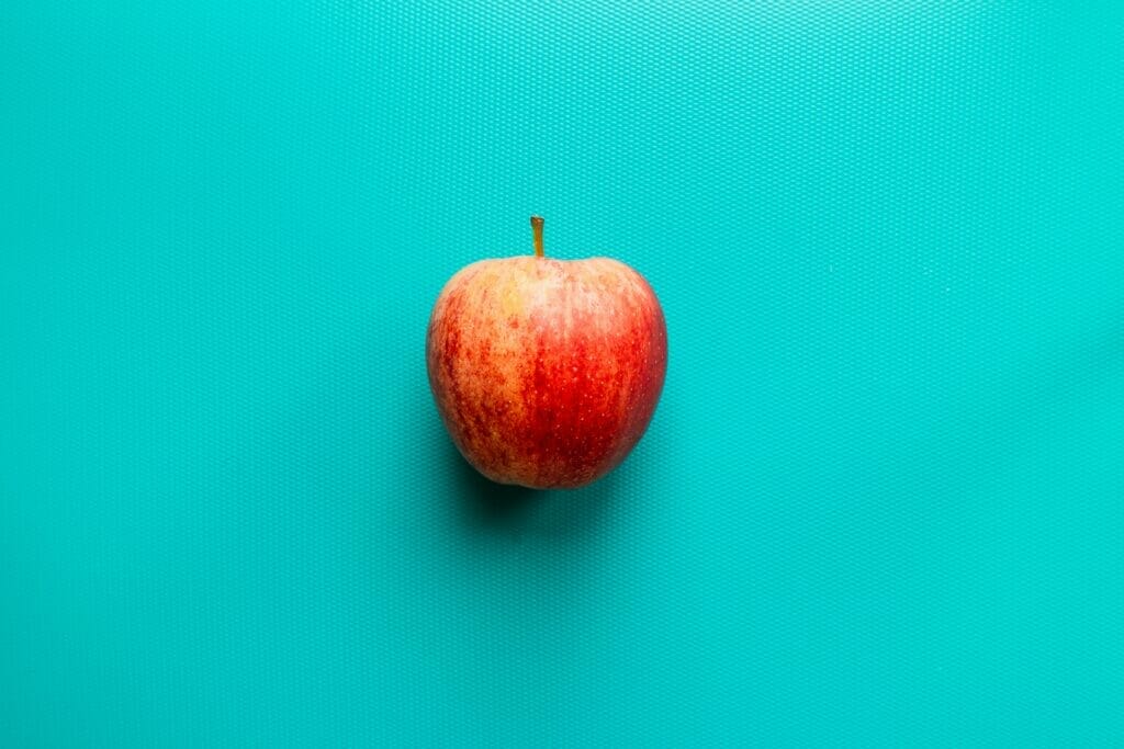 red apple fruit on blue surface